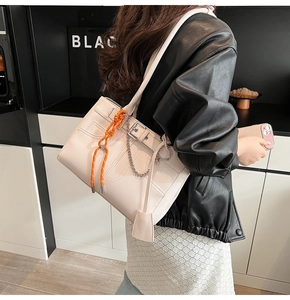 Détail du sac cabas blanc cassé avec chaîne argentée et pendentif tressé orange