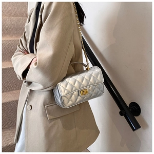 Detailed close-up of silver quilted texture and gold twist lock on the mini handbag