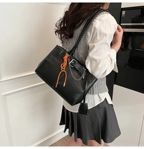 Vue détaillée du sac cabas noir avec coutures blanches et charme de corde orange