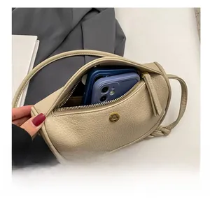Interior view of beige crescent bag showing capacity for two smartphones and hardware