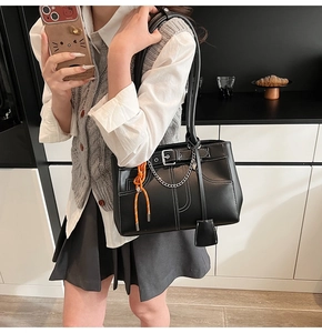 Detail of black leather tote bag with white contrast stitching and metallic chain strap
