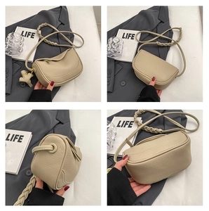 Detail of beige lychee texture leather saddle bag with woven strap and elephant charm