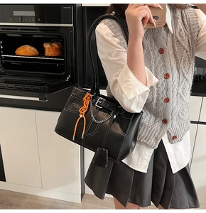 Detail of black leather tote bag with white contrast stitching and orange rope accessory