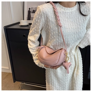 Close-up of pink pebbled leather dumpling bag with woven strap and elephant charm detail