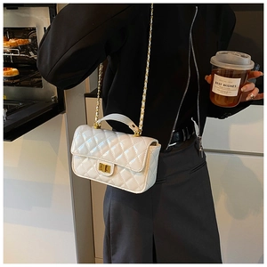 Detail of white quilted patent leather bag with gold chain strap and turn-lock closure
