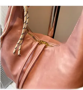 Détail de la double fermeture éclair dorée et de la bandoulière tressée du sac rose