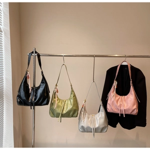 Détail de sacs hobo en quatre couleurs en similicuir souple avec pompons tressés