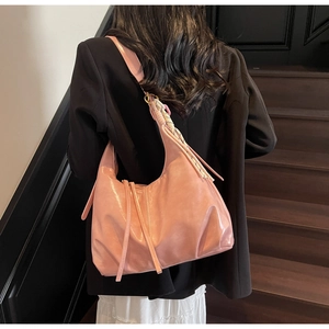 Détail du sac hobo rose avec foulard rayé et lanières décoratives sur le côté