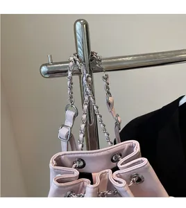 Detail of pink bucket bag featuring silver eyelets and metal chain shoulder strap