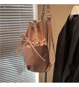 Detail of pink faux leather bucket backpack featuring drawstring closure and ribbon bow accent