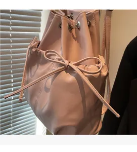 Detailed macro view of the pink drawstring bucket bag with decorative bow and PU leather texture