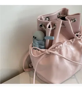 Detail of light pink bucket bag side pocket holding a small umbrella for utility