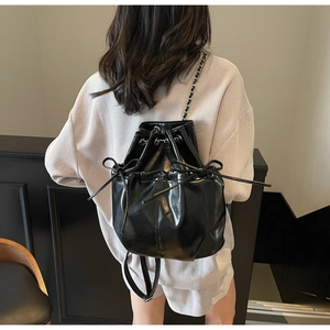 Detail of black glossy PU leather bucket backpack with drawstring and bow knot decor