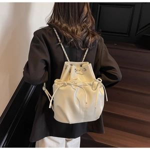 Rear view of model wearing cream PU leather drawstring backpack with bow detail