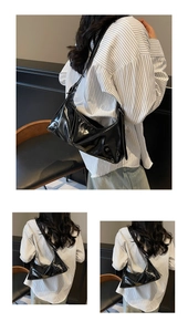 Detail einer schwarzen Lackleder-Schultertasche mit Metallnieten und Schnallen