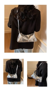 Detail der silbernen Metallic-Tasche mit Faltenstruktur und Nietendekor für Damen