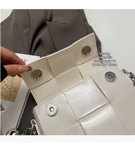Détail du sac tressé blanc avec boucles magnétiques argentées et bandoulière chaîne