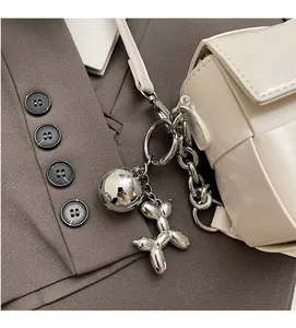 Détail du charm chien ballon argenté et pendentif rond sur un sac à main tissé blanc