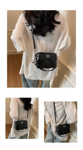Détails d'un sac carré tissé noir avec chaîne argentée et pendentif sphérique élégant