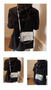 Détail d'un sac bandoulière carré tissé argenté avec chaîne métallique et pendentif