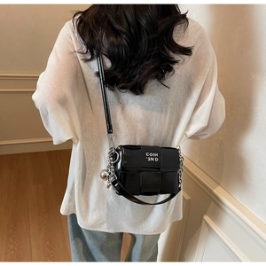 Détail du sac bandoulière tressé noir avec chaîne argentée et logo COIH blanc