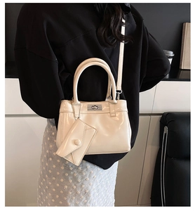 Detail view of cream white patent leather bucket bag with silver clasp and mini pouch