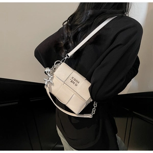 Détail du sac bandoulière blanc tissé avec chaîne argentée et breloque chien ballon