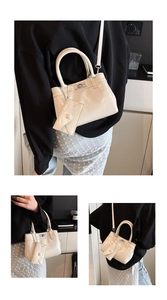 Detail view of cream patent leather handbag with silver twist lock and mini charm bag