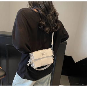 Détail du sac bandoulière tressé blanc avec logo métallique argenté et breloque sphérique