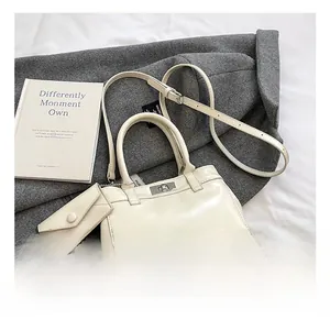 Detail of off-white leather bucket bag featuring silver twist lock and mini charm pouch
