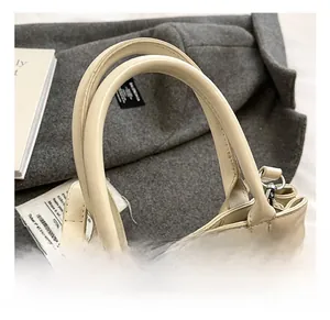 Detail of a beige leather tote with reinforced stitching and shiny silver metal hooks