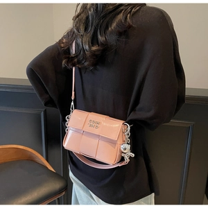 Détail du sac bandoulière tissé rose clair avec breloque lapin argentée et logo