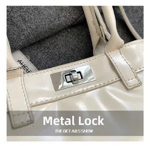 Close-up of the silver metallic turn-lock closure on a cream leather handbag