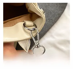 Detailed close-up of high-quality silver metallic hook on a beige leather handbag