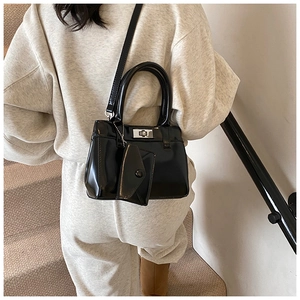Detail view of black patent leather bucket bag with silver twist lock and mini pouch