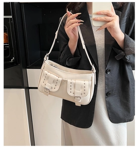 Close-up of retro cream motorcycle shoulder bag featuring silver rivets and small buckle pockets