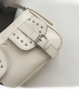 Close-up of cream white leather bag with silver rivets and buckle in vintage style