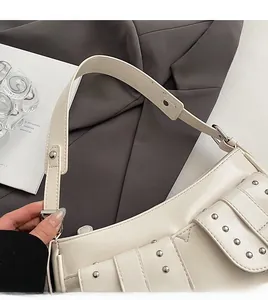 Detail view of cream white shoulder bag featuring silver punk rivets and wide strap