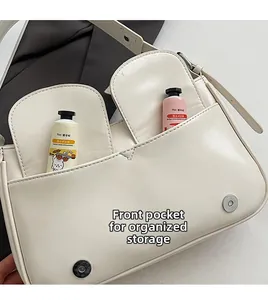 Detail of off-white leather bag with front pockets and magnetic silver button closure