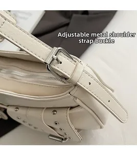 Detail of adjustable silver buckle strap and metal rivet studs on cream leather bag