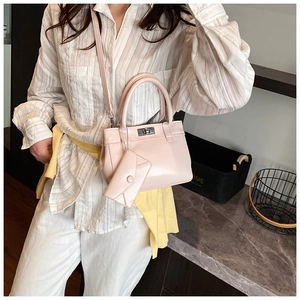 Detail of light pink faux leather handbag with silver twist lock and small envelope charm