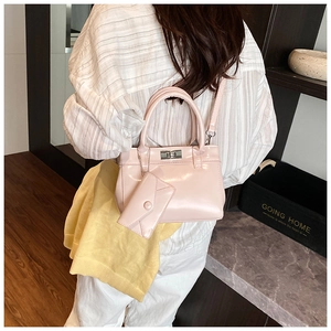 Pink patent leather bucket bag with silver lock and mini charm on a model's arm