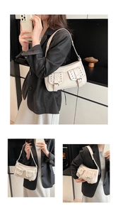 Detail showing creamy white underarm bag with metal studs and buckle pocket design