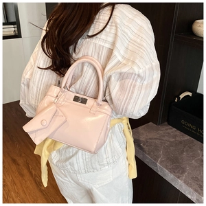 Détail du sac à main en cuir verni rose avec fermoir rotatif argenté et breloque
