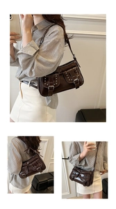 Detail of dark brown glossy leather shoulder bag featuring punk rivets and buckle straps