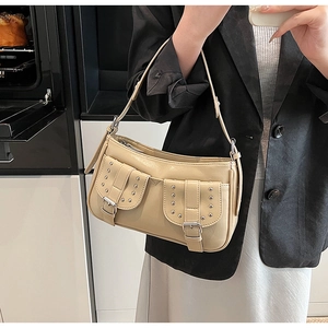 Detailed view of beige vintage rivet shoulder bag with silver buckles and two front pockets