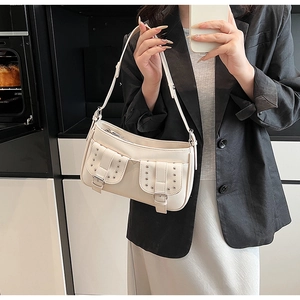Detail of a creamy white PU leather hobo bag featuring silver rivets and utility buckles