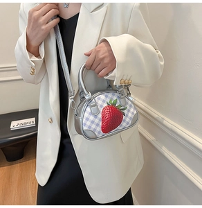 Detail der silbernen Mini-Tasche mit Karomuster und Erdbeerdruck zu weißem Blazer
