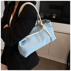 Vista lateral de un gran bolso tote de tela vaquera azul llevado por una modelo en interior