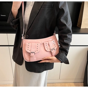 Detail of pink patent leather shoulder bag featuring silver rivets and small flap pockets